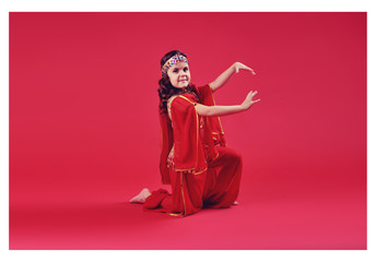 Close up shot of a belly dancer wearing a blue, gold and green costume shaking her hips. Isolated on white. Clipping path included so image can be easily transferred to a different colored background.