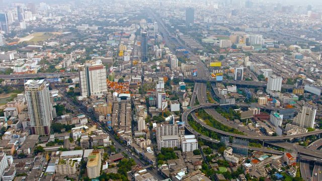 Overlooking shot of Bangkok's sprawling cityscape, with traffic on a modern and complex highway system, as well as highrise urban architecture. Video UltraHD