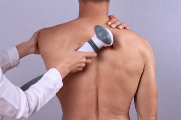 Therapist doing healing infrared treatment on man's back . Alternative medicine, physiotherapy,...