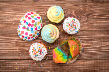 Brightly colored cupcakes on the wooden table. 