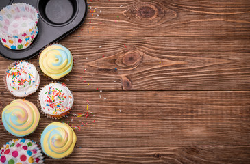 Brightly colored cupcakes on the wooden table. Backgrounds.