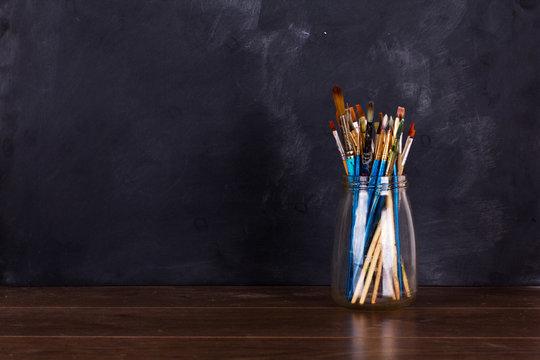 Paint Brushes In A Pot Against A Black Background