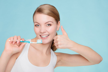 woman holds toothbrush with toothpaste cleaning teeth