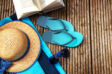 summer vacation, accessories for beach holidays and a book on wooden planks, top view