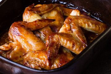 Baked chicken wings with barbecue sauce in clay bowl