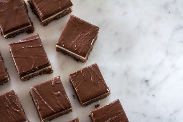 Chocolate Peppermint Slice Cut Up on Marble Cutting Board from Above with Copy Space