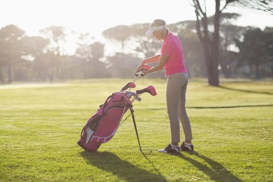 Side view of woman putting golf club in bag 