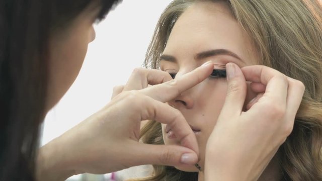 Makeup artist sticks the eyelashes to the girl