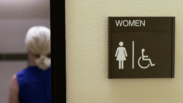 woman walking into an office womans restroom 4k