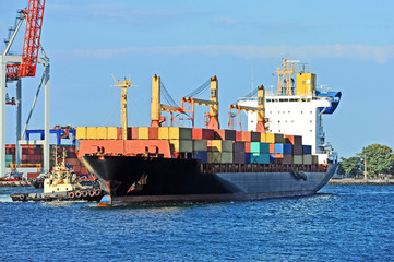 Fototapeta premium Tugboat assisting container cargo ship
