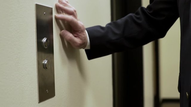impatient businessman pressing the elevator button and tapping on the wall