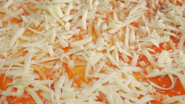 Cheese parmesan pieces adding on pizza in 4K 3840X2160 UHD video - Cheese sprinkling over pizza base 4K 2160p UHD footage 