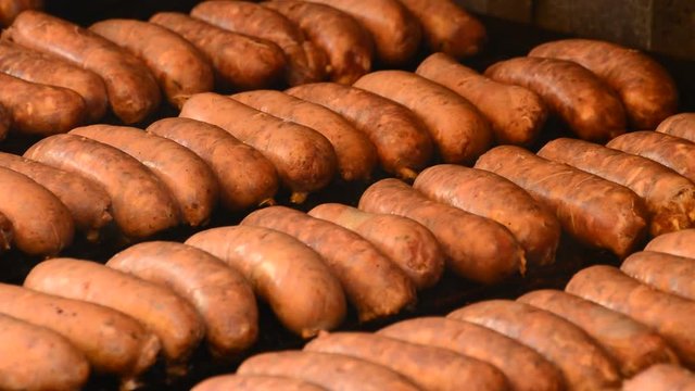 Hot dog, sausage or frankfurter cooking at grill