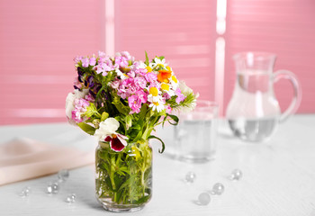 Meadow flowers bouquet in glass vase on table