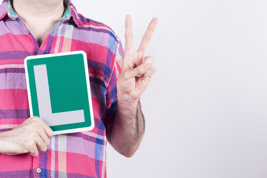 Average Man Wearing A Shirt, Holding His Learner Car Driver Plate (a L Sign). Spanish Model, Other Countries May Vary.