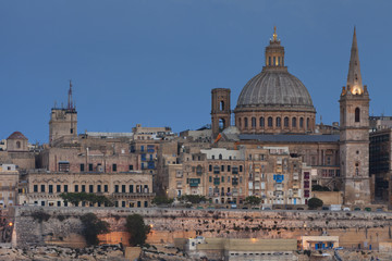 Fototapeta na wymiar Close view of the medieval city of La Valletta with the bell tower and dome of the Basilica of Our Lady of Mount Carmel 