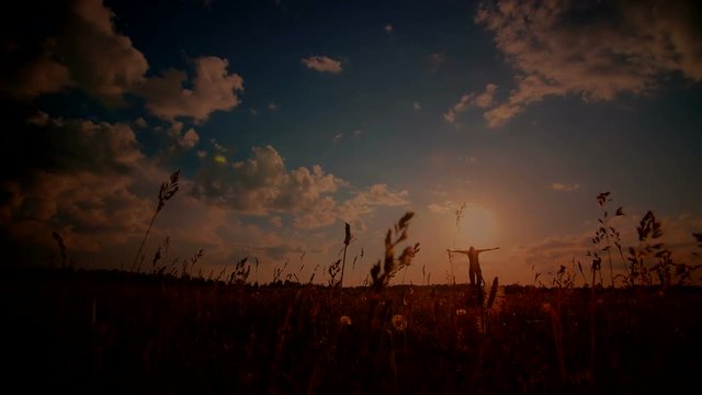 Young girl with outspread hands have fun at sunset in the field