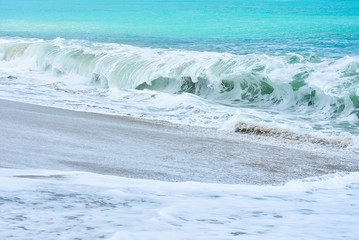 An ocean shorebreak in front view. Big beautiful green blue wave splashing with backwave and ready to break out. White foam sliding over sand. powerful ocean waves breaking natural background, Phuket