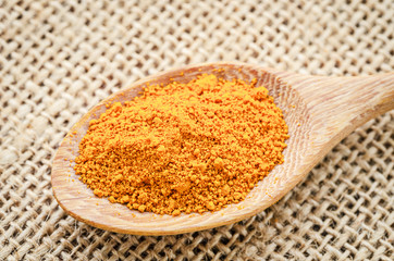turmeric powder in wooden spoon.
