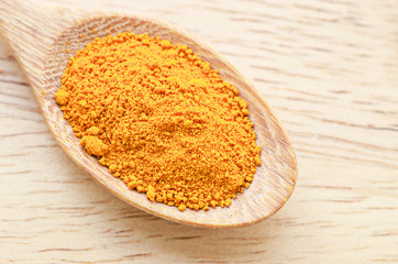 turmeric powder in wooden spoon.