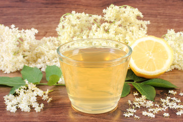 Fresh healthy juice, elderberry flowers and lemon on rustic board