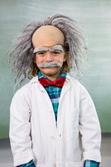 Smiling boy dressed as scientist standing against board - obrazy, fototapety, plakaty