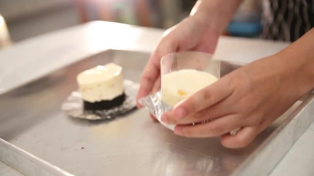 Hand wrapping plastic and foil around cheese cake tart