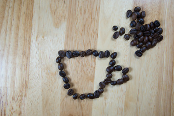 Coffee beans make into coffee cup shape on wood background