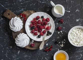 Raspberry, black currant, cheese, cream, honey, meringue - tasty breakfast or snack. On a dark background