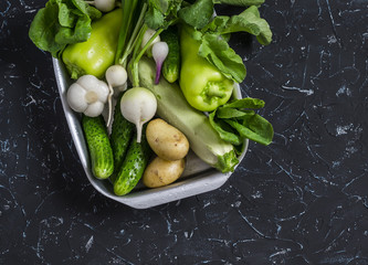 Fresh green and white vegetables - cucumbers, peppers, radish, radish, garlic, onion, potato, zucchini  on a dark background. Healthy vegetarian food