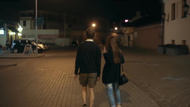 Young couple walking along the street in the evening