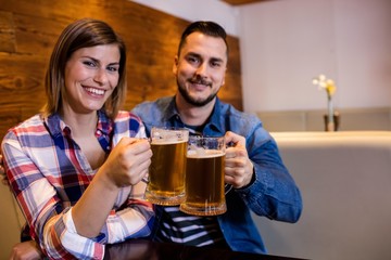 Cheerful couple toasting beer mug