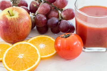 Close up of fresh juice glass and fruits on table - healthy eati