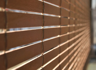 Brown wooden blinds rolled out and hanging outside a residential home