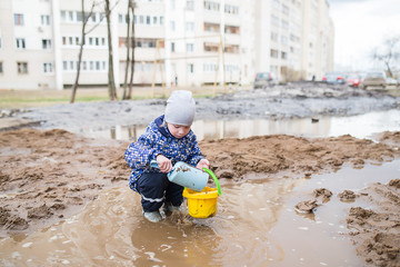 Boy playing in a muddy puddle