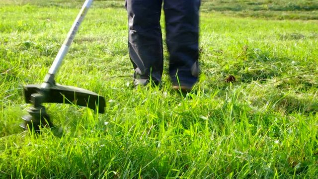 Worker mowing grass trimmer closeup slowed