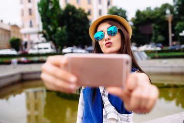 Young smiling teen happy woman making selfie on the street, glasses, traveling alone, having fun,...