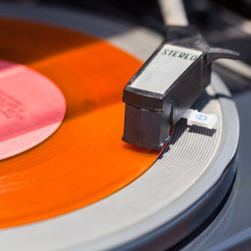 tonearm of turntable on orange vinyl record