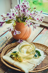 Glass cup of tea with linden on wooden table on window background