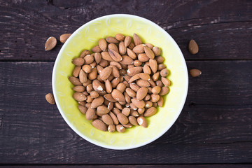 Almonds in Yellow Bowl on Dark Wooden Background, Healthy Food, Paleo Food, Top View, Close-up