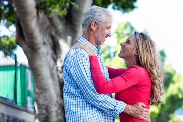 Romantic mature couple hugging against tree