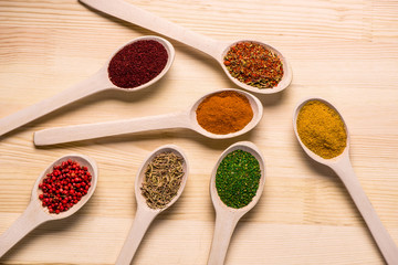 Spices in spoons on wooden table