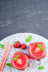 Strawberry smoothies in glass jar, berries and mint on stone background with copy space. Healthy food concept