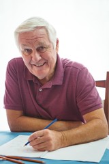 Portrait of  a smiling retired man writing on white paper