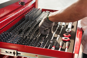 Hand picks a tool for car repair - 115294511