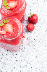 Summer drink strawberry smoothies in glass jar, berries and mint on white background with copy space. Vegetarian food