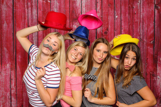 Junge Frauen haben Spaß mit einer Fotobox - Mädchen mit Hüten und Bärte 