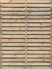A section of brown, vertical, overlapped wooden garden fence in closeup in the sun with shadows