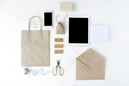 Desk Workspace With Tablet, Phone, Craft Envelopes On White Background. Flat Lay, Top View