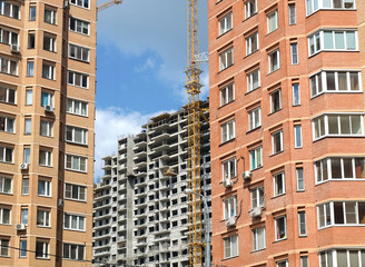 Fototapeta na wymiar Urban scene. Construction of city district. Constructed brick houses in the foreground and construction of concrete building on the far. Photo in sunny day